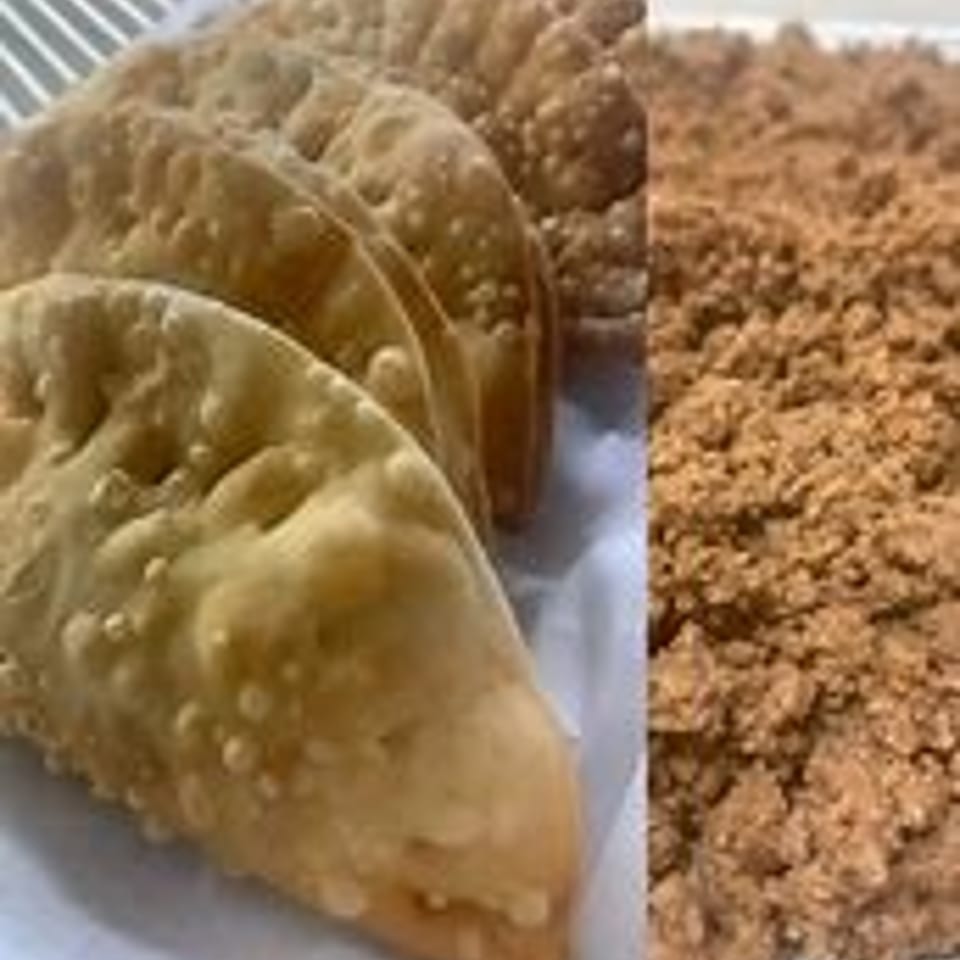 Golden-brown fried empanadas with a side of crumbled brown sugar.