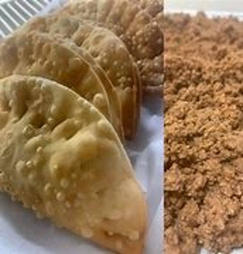 Golden-brown fried empanadas with a side of crumbled brown sugar.