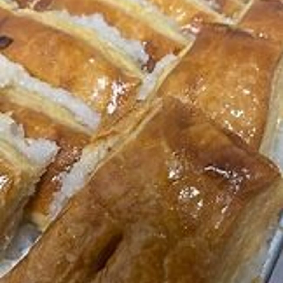 Close-up of golden-brown pastries with a sweet glaze and white sugar filling.