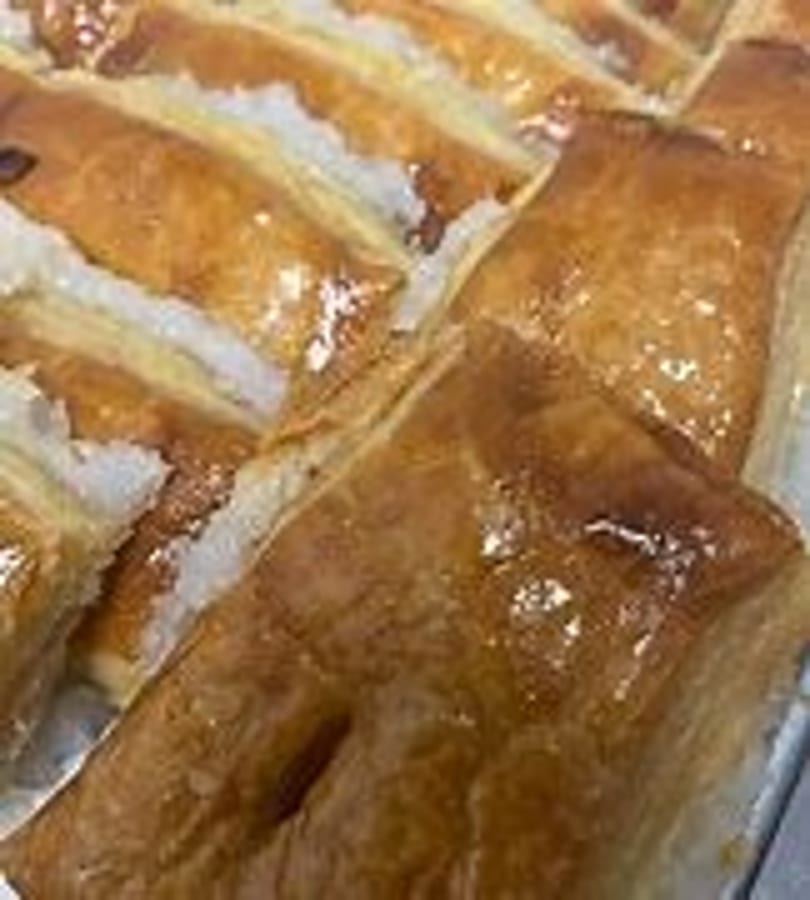 Close-up of golden-brown pastries with a sweet glaze and white sugar filling.