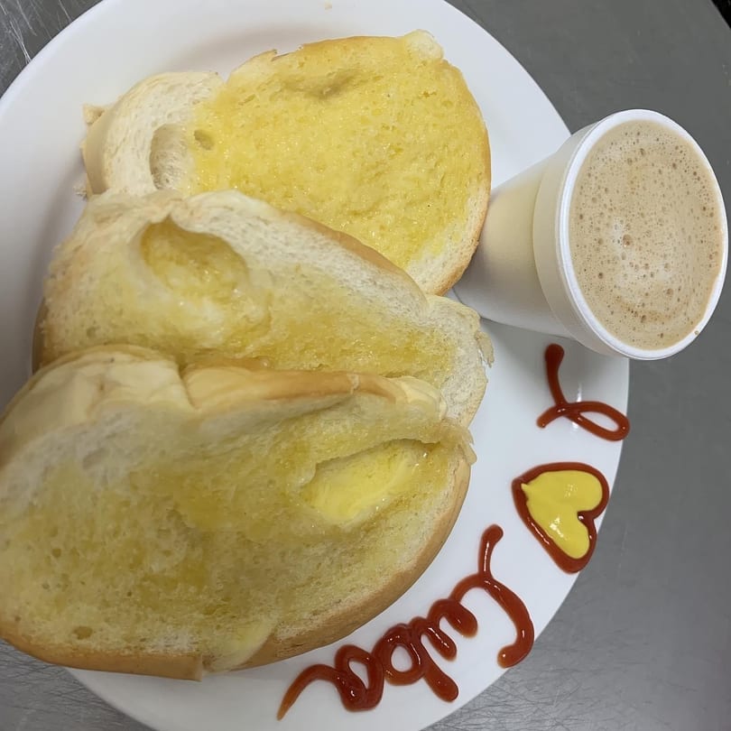 Buttered Cuban bread slices and a cup of coffee on a white plate with "I love Cuba" written in ketchup.