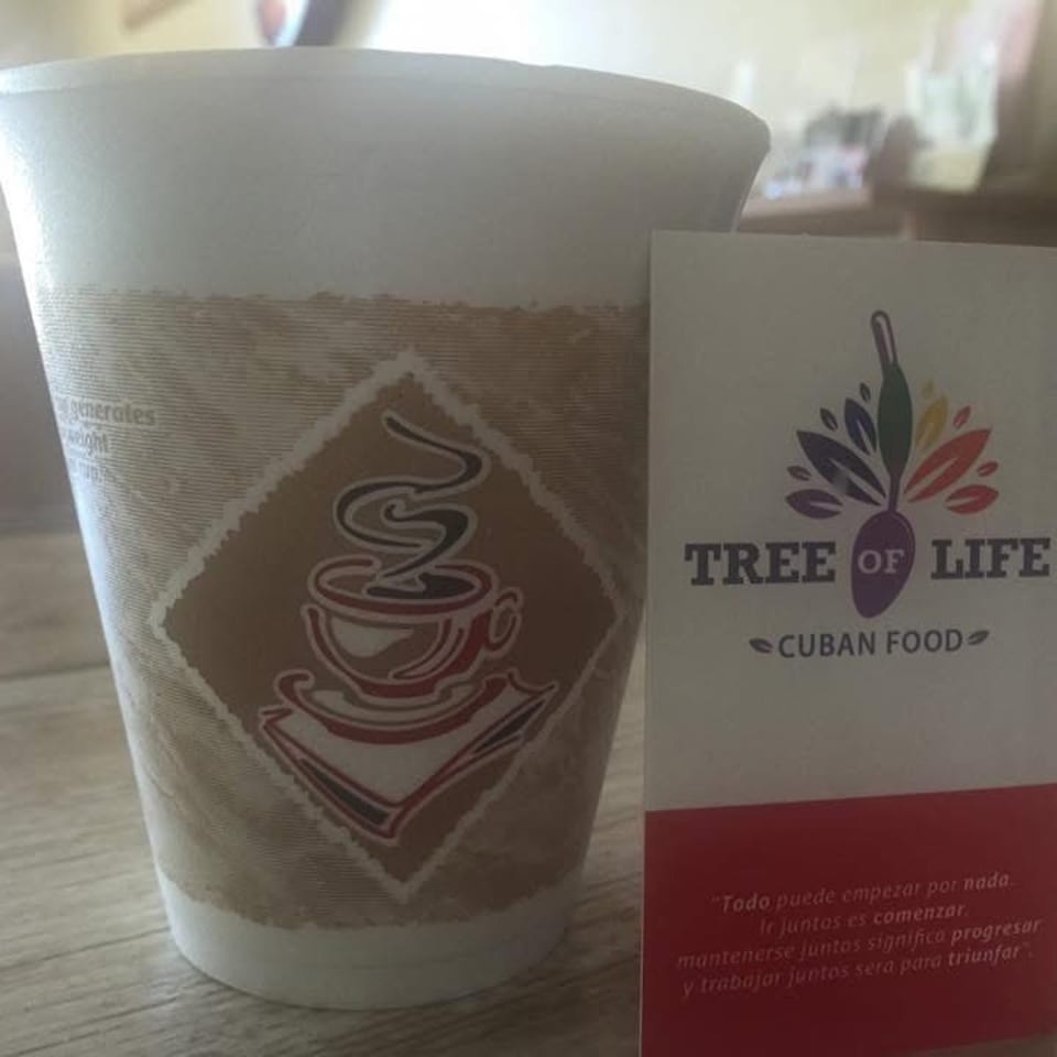A coffee cup with a coffee logo next to a "Tree of Life Cuban Food" business card.
