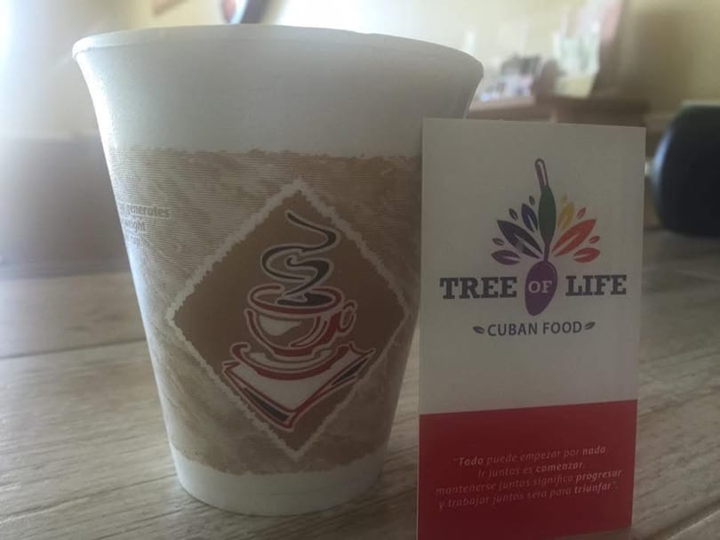 A coffee cup with a coffee logo next to a "Tree of Life Cuban Food" business card.