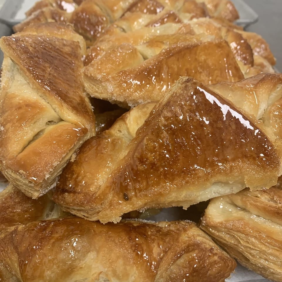 Close-up of golden-brown, glazed puff pastry turnovers with a sugary coating.