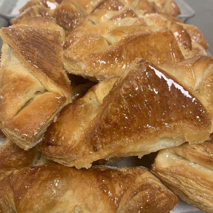 Close-up of golden-brown, glazed puff pastry turnovers with a sugary coating.